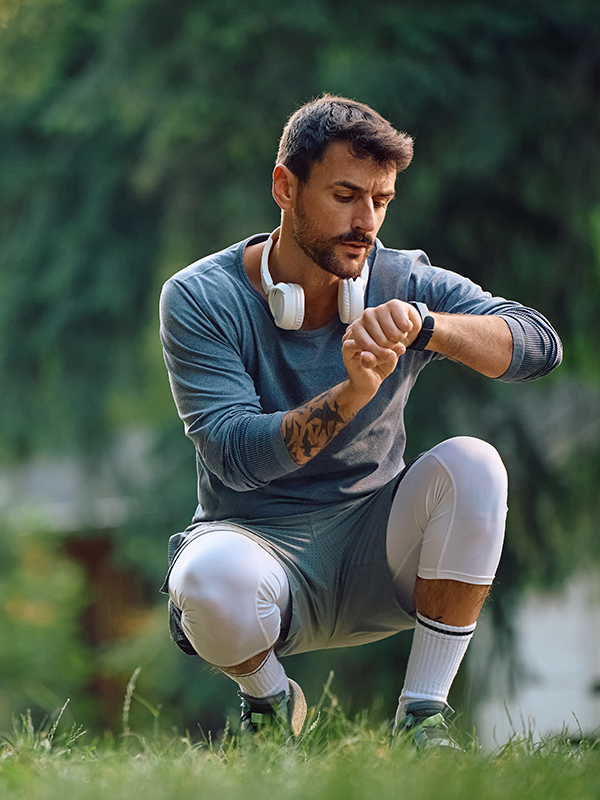 Mann in Sportkleidung, der auf seine Fitnessuhr schaut